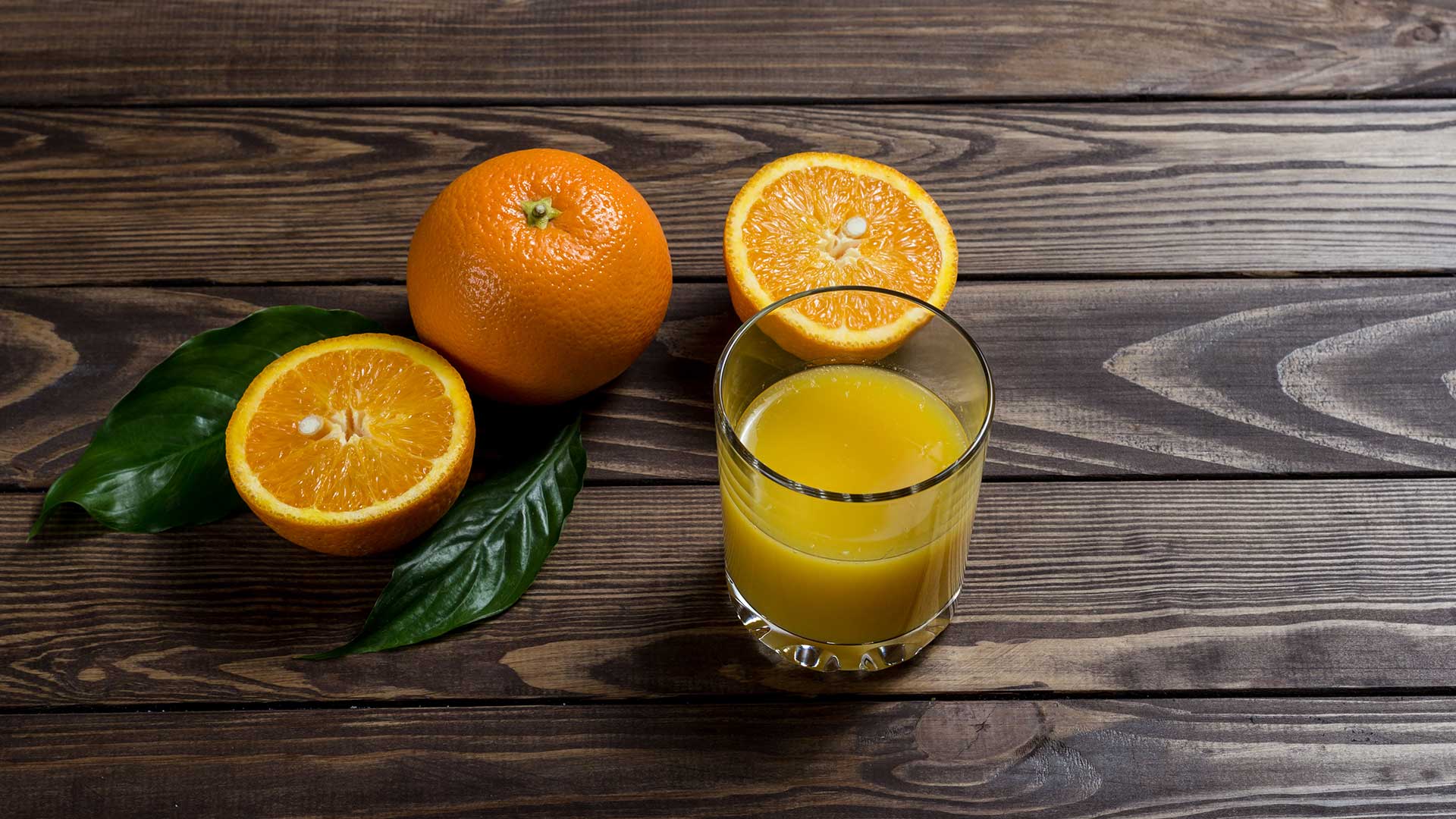 JDC - Glass of orange juice beside sliced orange fruit